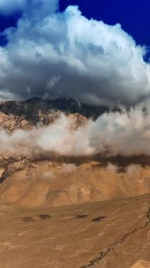 Dağların tepelerini kaplayan yumuşak beyaz bulutlar. Ölüm Vadisi 'ne havadan bak. Dikey video
