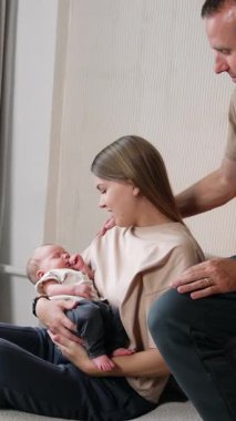 Çocuklu bir kadın kanepeye oturur. Koca kanepeye oturup bebeğe bakıyor ve karısını okşuyor. Dikey video