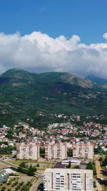 Karadağ 'daki yeşil dağların eteklerine dağılmış Bar kenti manzarası. Muhteşem kayaların tepesinde beyaz bulutlar toplanıyor. Dikey video