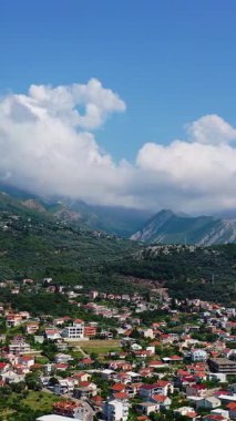 Karadağ 'ın Bar kentinin parlak güneşli manzarası. Yeşil dağların eteklerine dağılmış şehir manzarası. Hava görüntüsü. Dikey video