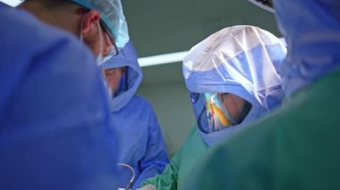 Üniformalı sağlık görevlileri ameliyatta işbirliği yapıyor. Cerrahlar travma cerrahisinde koruyucu kask takarlar..