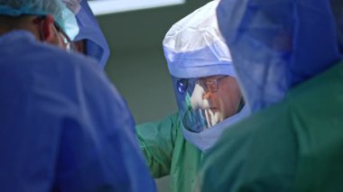 Koruyucu kask takan baş cerrah ameliyat sırasında tokmak kullanıyor. Travma ameliyatı devam ediyor..