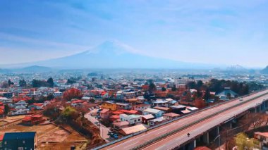 Arabalar Tokyo şehir manzarasından geçen otoyoldan geçer. Arkadaki sisli havada muhteşem Fuji Dağı. Hava görünümü.