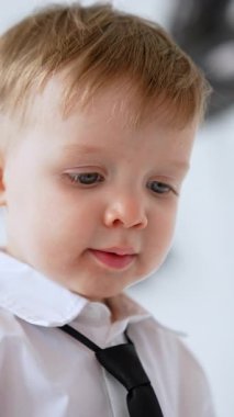 Beyaz gömlek ve siyah kravat takan iki yaşında beyaz bir çocuk. Şirin bir bebeğin yakın portresi. Dikey video.