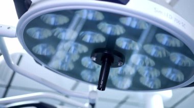 Ameliyathane odasının tavanında büyük yuvarlak lamba kapalıydı. Modern tıbbi aydınlatma ekipmanları. Kapat..