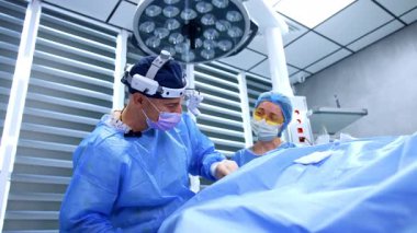 Pozitif erkek doktor plastik cerrahide metal aletleri ileri geri itiyor. Sarı gözlüklü kadın hemşire asistanı. Kapat..
