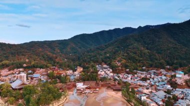 Japonya 'nın Miyajima adasındaki yerleşim alanı yakınlarındaki kayaları sık ormanlar kaplar. Düşük gelgitte muhteşem Itsukushima Tapınağı 'nın üstündeki drone görüntüleri..