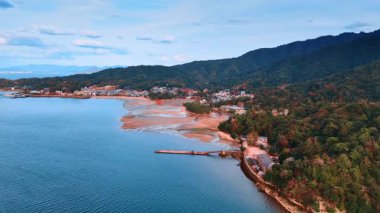 Japonya 'nın Miyajima adasındaki ünlü kırmızı Grand Torii Kapısı' yla kıyıda gelgit dönemi. İnsansız hava aracı görüntüleri yerleşim alanının ve muhteşem ağaçlık dağların manzarasını gösteriyor..