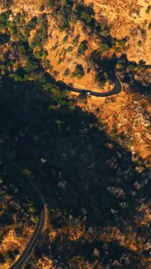 Dalgalı yol ile dağlık araziyi geçti. Kaliforniya kayalık manzarası gün batımında tepeden. Dikey video