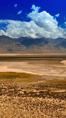 Kaliforniya çölünde çeşitli türde araziler. Muhteşem çıplak kayalar arka planda bulutlarla gölgelenmiştir. Ölüm Vadisi 'nin üst görüntüsü. Dikey video