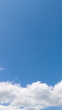 Beyaz kabarık bulutlu, gök mavisi bir yaz. Atmosferde yumuşak bulutlar var. Düşük açı. Zaman ayarlı. Dikey video