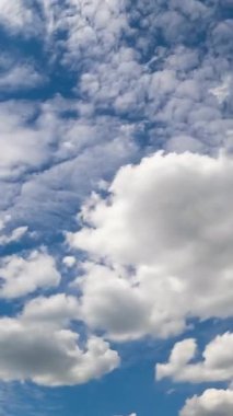 Atmosferdeki çeşitli bulut türleri. Kümülüs ve mavi gökyüzündeki beyaz bulutlar. Düşük açı. Zaman ayarlı. Dikey video