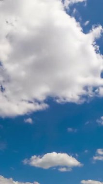 Yumuşak kabarık bulutlarıyla inanılmaz bir yaz gökyüzü. Arka planda Stratus bulutları uçuşuyor. Düşük açı. Zaman ayarlı. Dikey video