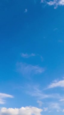 Yazın inanılmaz masmavi gökyüzü. Kümülüs bulutları ufku ve güneşi kaplıyor. Düşük açı. Zaman ayarlı. Dikey video