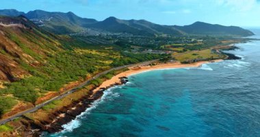 Pasifik Okyanusu 'nun sinemanın kayalık kıyısındaki sakin mavi su manzarası. Otoyol kıyı şeridi boyunca uzanıyor. Çarpıcı dağlarla çevrili yerleşim alanı. Hava perspektifi.