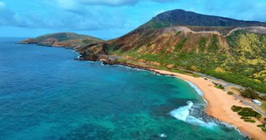 Köpüklü dalgalar, Hawaii, ABD 'deki Oahu Adası' nın pitoresk dağlarındaki kumlu plaja ulaşır. Kıyı şeridindeki çarpıcı kayalar boyunca görüntüler. Hava perspektifi.
