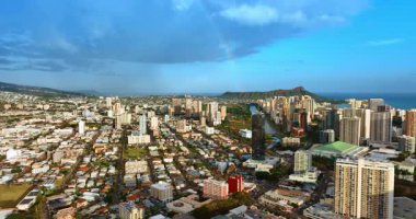 Düşük katlı ve yüksek binalı mimarisi olan şehir merkezinin üstünde uçuş. Gökkuşağı arka planda Koko Krateri 'ne dokunuyor. Hawaii, ABD 'deki Oahu Adası' ndaki hava manzarası..