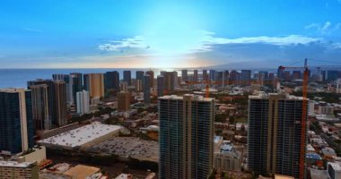 Pasifik Okyanusu 'nun kıyı şeridinde çok katlı bir bina var. Bina vinçleri ön planda görülür. Honolulu Sahnesi, Oahu, ABD. Üst görünüm.