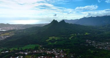 Yeşilliklerle kaplı çarpıcı dağa yaklaşıyoruz. Düşük katlı evler muhteşem kayaları çevreliyorlar. Oahu, Hawaii, ABD manzarası. Üst görünüm.