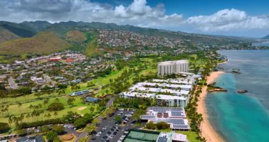 Pasifik Okyanusu kıyısındaki inanılmaz kumlu plajlar, konut evleri ve palmiye ağaçları. Bulutlar arka planda dağların üzerinde toplanır. Honolulu, Oahu, ABD manzarası. Hava perspektifi.
