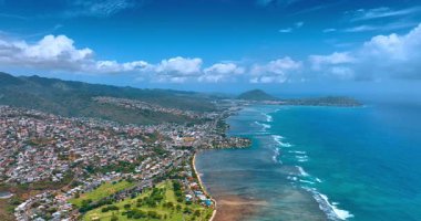Hawaii kıyısındaki Pasifik Okyanusu 'nun muhteşem turkuaz su manzarası. Honolulu şehri adanın dağlık arazisine dağılmış durumda. Hava görünümü.