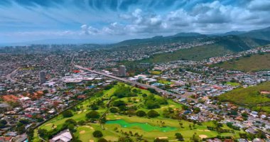 Düşük katlı binalarla çevrili güzel yeşil parkın üzerinde insansız hava aracı uçuşu. Güneşli Honolulu 'nun engin manzarası, Hawaii, ABD.