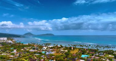 Villaların üzerinde uçan palmiye ağaçları Pasifik Okyanusu 'nun kumlu egzotik sahillerine yaklaşıyor. Gök mavisi su yüzeyinin üzerinde asılı devasa bulutlar. Honolulu, Hawaii, ABD.