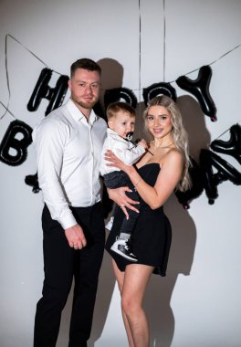 Doğum günü arkaplan partisi. Bir aile, arka planda şenlikli süslemeler ve yüzlerinde neşe dolu bir doğum günü kutlaması için birlikte poz verir..