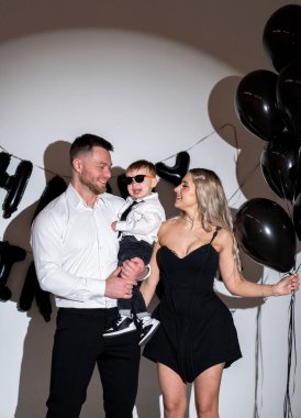 Balonlarla ve gülücüklerle kutlama. Neşeli bir aile bir partide siyah balonlarla poz verir, birbirlerine eşlik ederler ve kalıcı anılar yaratırlar..
