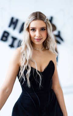 Zarif bir doğum günü kutlaması! Genç bir kadın, doğum günü için göz kamaştırıcı siyah bir elbise ve şık aksesuarlarla rahatça poz veriyor..