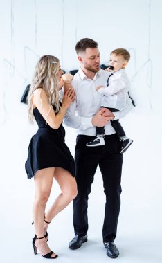 Şık giyinmiş bir aile kutlaması. Bir aile birlikte poz verir, zarif giyinir, gülümser, parlak, minimalist bir ortamda özel bir anın tadını çıkarır..