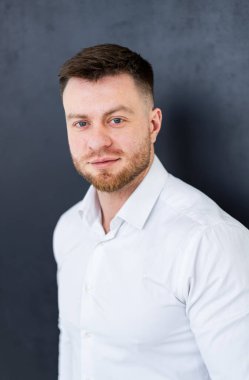 Siyah arka planda takım elbiseli bir adam. İyi giyimli bir adam kameraya özgüvenle bakar, profesyonel bir tavır ve temiz bir görünüm sergiler..