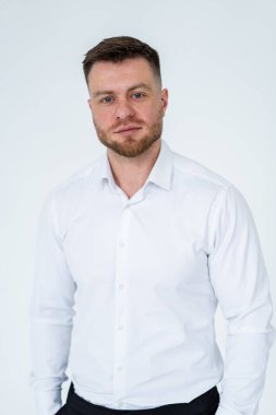 Beyaz gömlekli profesyonel bir adam poz veriyor. Tarafsız bir zemine karşı duran beyaz gömlekli bir adam..