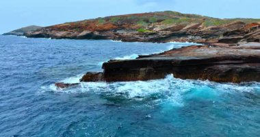 Hawaii, ABD 'nin bakımsız sahillerinde dalgalar savruluyor. İnsansız hava aracından kayalık kıyı şeridine bak.