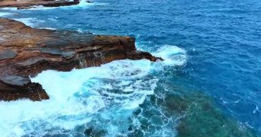 Güçlü beyaz dalgalar Pasifik Okyanusu kıyısındaki güçlü kayalara çarpıyor. Hawaii, ABD açıklarında insansız hava aracı görüntüleri..