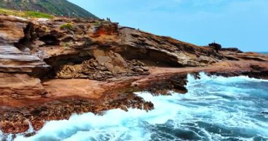 Turistler katmanlı kayaların üzerinde durup muazzam Pasifik Okyanusu 'nu seyrediyorlar. Hawaii 'nin kayalık sahili, ABD' nin su yüzeyinden görüntüsü.