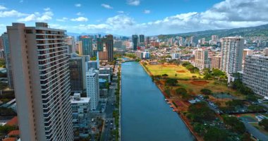 Ala Wai Kanalı, ABD 'nin Hawaii eyaletinin Honolulu şehrinde Waikiki' yi özetliyor. Havadan bakış açısı. Arkaplanda dağ aralığı ve mavi bulutlu gökyüzü.
