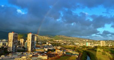 Gün batımında Honolulu manzarasının üzerinde devasa bulutlar toplandı. Güzel, parlak gökkuşağı şehrin üzerinde yükseliyor. Hawaii, ABD.