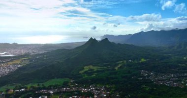 Yeşilliklerle kaplı dağın şaşaalı manzarası. Kayaların etrafında büyük yerleşim alanları var. Honolulu, Hawaii, ABD. Hava görünümü.