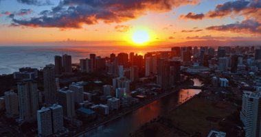 Ufkun arkasında saklanan parlak batan güneş çemberi. Su yüzeyine yansıyan yumuşak ışık. Gün batımında Waikiki, Honolulu, Hawaii, ABD 'de hava manzarası.