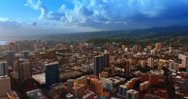 Honolulu, Hawaii, ABD 'nin engin şehir manzarasının üzerindeki görüntüler. Arka planda dağların üzerinde dramatik bulutlar oluşuyor.