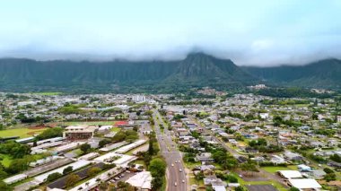 Honolulu, Hawaii, ABD 'nin alçak şehir manzarası. Göz kamaştırıcı yeşil dağ sırası ve arka planda bulutlu bir manzara. Hava görünümü.