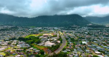 Geniş otoyolun üzerindeki görüntüler şehir manzarasını geçiyor ve yeşil dağlara çıkıyor. Güçlü kayalar gri bulutlarla kaplıdır..