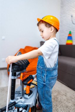 İçeride oynayan çocuk müteahhit. Turuncu şapkalı bir çocuk, rahat bir oturma odasında oyuncak yapımıyla özenle çalışır..