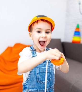 Çocuk oyuncak setiyle oynuyor. Genç çocuk heyecan verici bir şekilde yumuşak oyuncaklarla dolu renkli bir salonda inşa edilen bir oyuncakla meşgul..