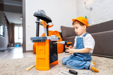 İçinde tezgah olan çocuk oyuncakları. Küçük bir çocuk, halının üzerinde otururken küçük bir matkap kullanmaya odaklanmış oyuncak tezgahıyla inşa etmekten zevk alır..