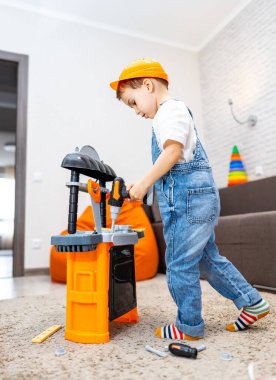 Çocuk oyuncaklarla oynuyor. Güvenlik şapkası takan genç bir çocuk, yaratıcı projeler yapmak için araçlar kullanarak, oyuncak tezgahında özenle çalışır..