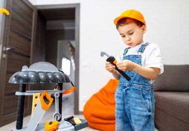 Çocuk aletlerle yaratıcı bir şekilde oynuyor. Oyuncak tezgahı tamir eden, yaratıcılık gösteren ve kapalı bir alanda odaklanan küçük bir çocuk..