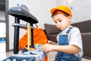 Çocuk oyuncak bloklarıyla oynuyor. Turuncu şapkalı küçük bir çocuk, kapalı alanda inşa edilmiş bir oyuncakla oynuyor, odak ve yaratıcılık gösteriyor..