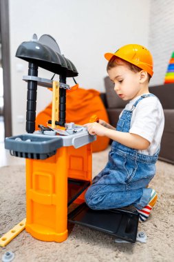 Çocuk oyuncaklarla oynuyor. Miğferli bir çocuk içeride bir oyun setiyle karşılaşır ve dikkatle bina faaliyetlerine odaklanır..